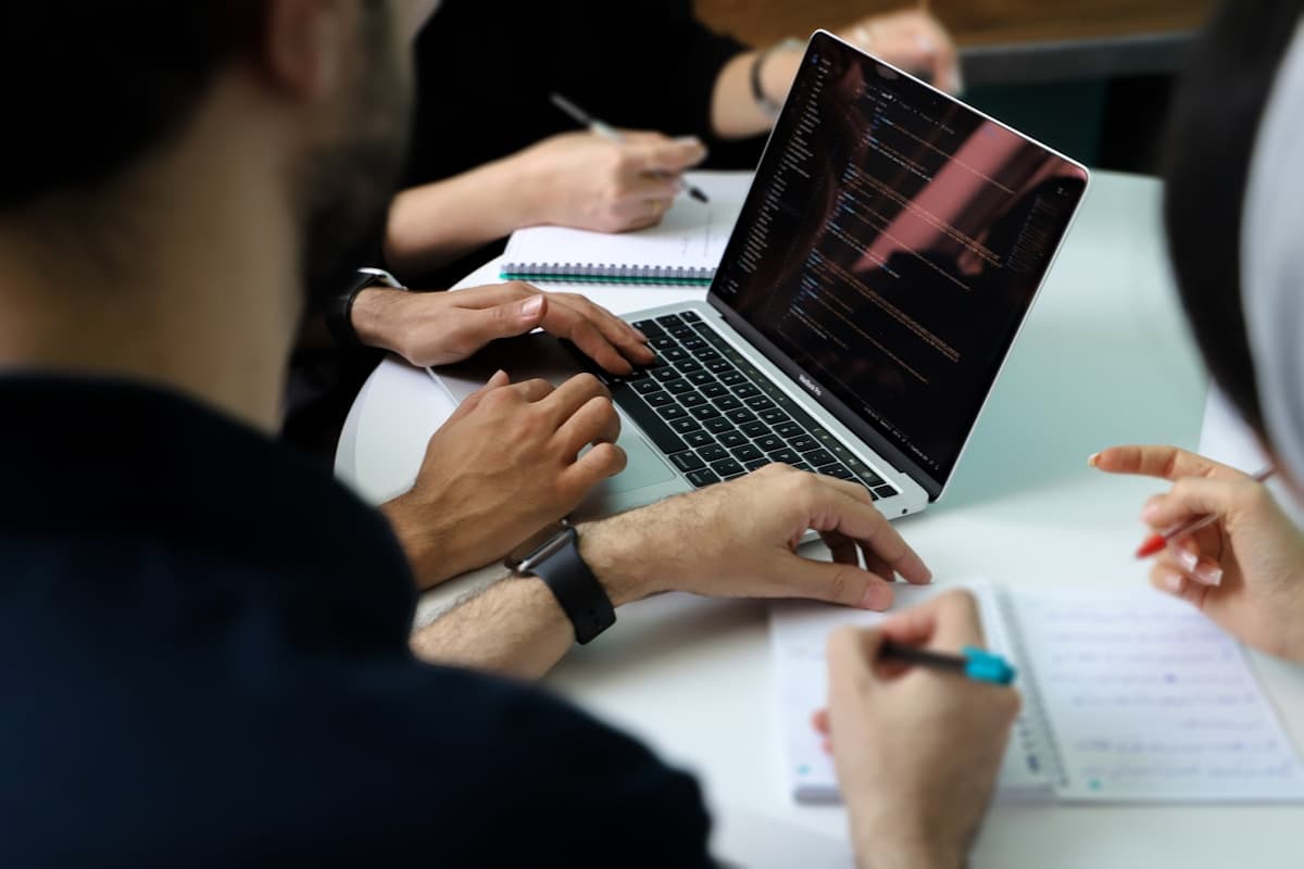 A group of people gathered around a laptop reviewing data