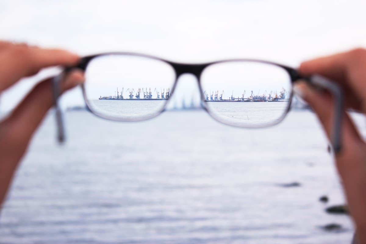 Person holding eyeglasses up to view the world clearly